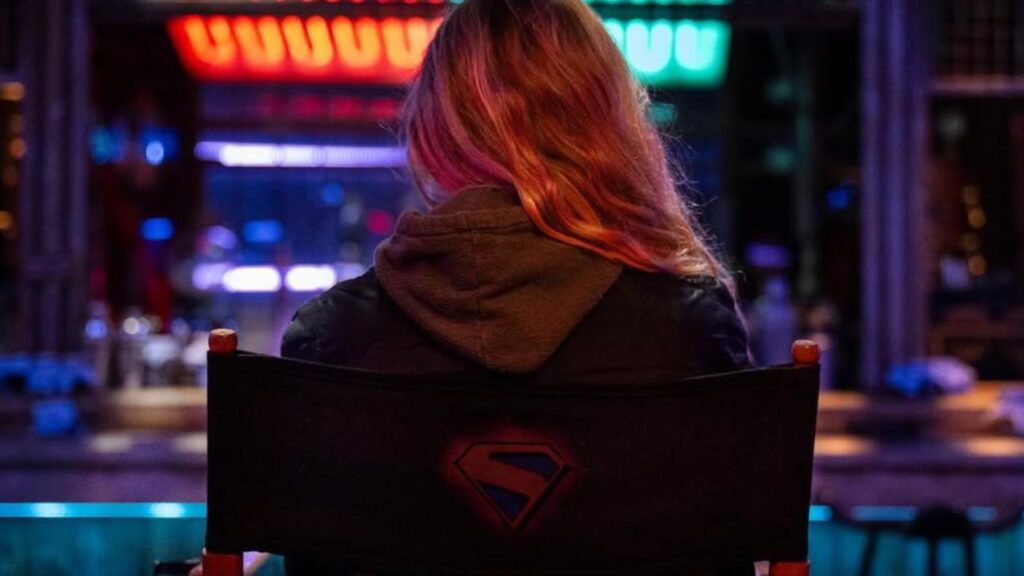 A imagem mostra a atriz Milly Alcock nos bastidores do filme da personagem Supergirl, prima do Superman
